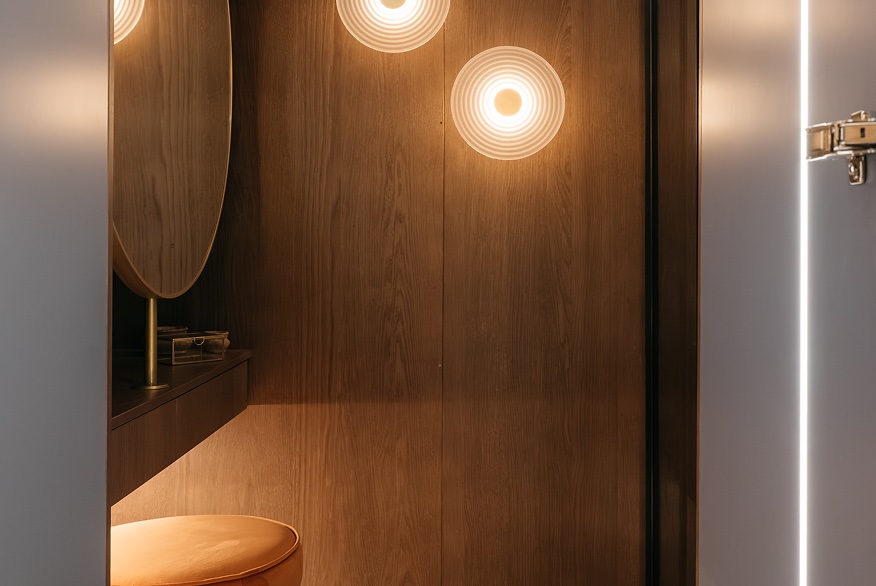 Warm timber bathroom with circular mirror and soft wall lighting